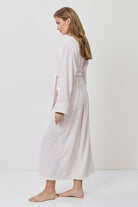 Woman wearing a white dress and cardigan on a plain background