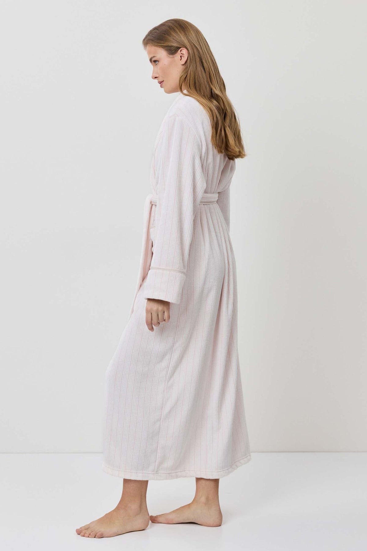 Woman wearing a white dress and cardigan on a plain background