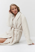 Woman wearing a white bathrobe against a plain background