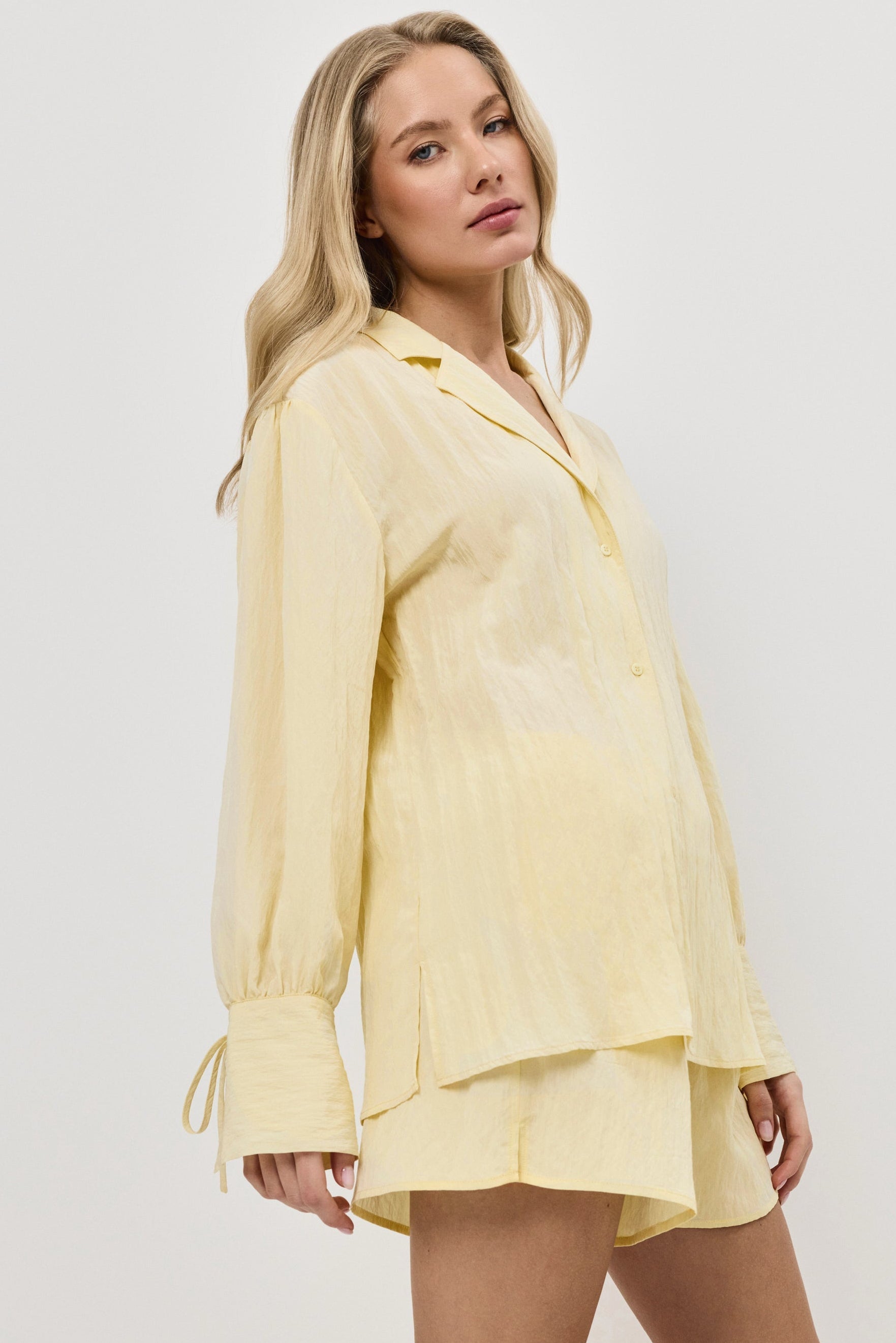 Woman wearing a yellow resort wear set with long sleeves and a shorts on a white background