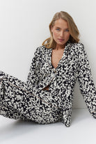 Woman wearing a black and white patterned pajama set against a white background