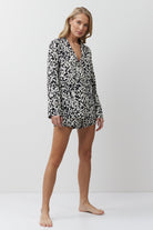 Woman wearing a black and white patterned pajama set on a white background