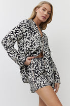 Woman wearing a black and white patterned pajama set on a plain background