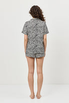 Person wearing a zebra print pajama shirt and shorts set on a white background