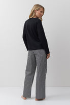 Woman wearing a black sweater and striped pants on a white background