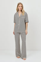 Woman wearing a patterned pajama set on a white background.