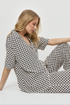 Woman wearing a patterned pajama set on a plain background