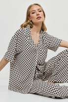 Woman wearing a patterned pajama set on a plain background