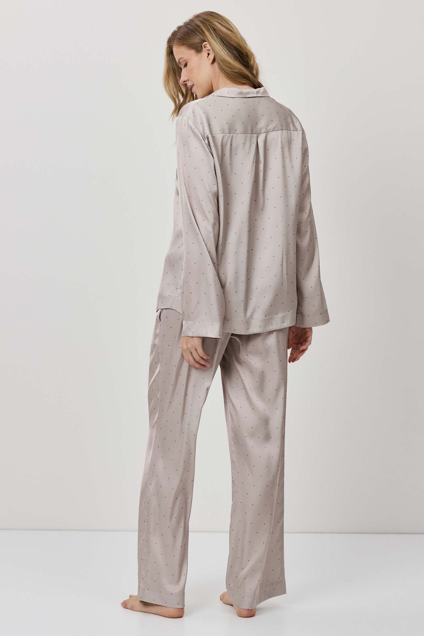 Person wearing a beige pajama set against a white background