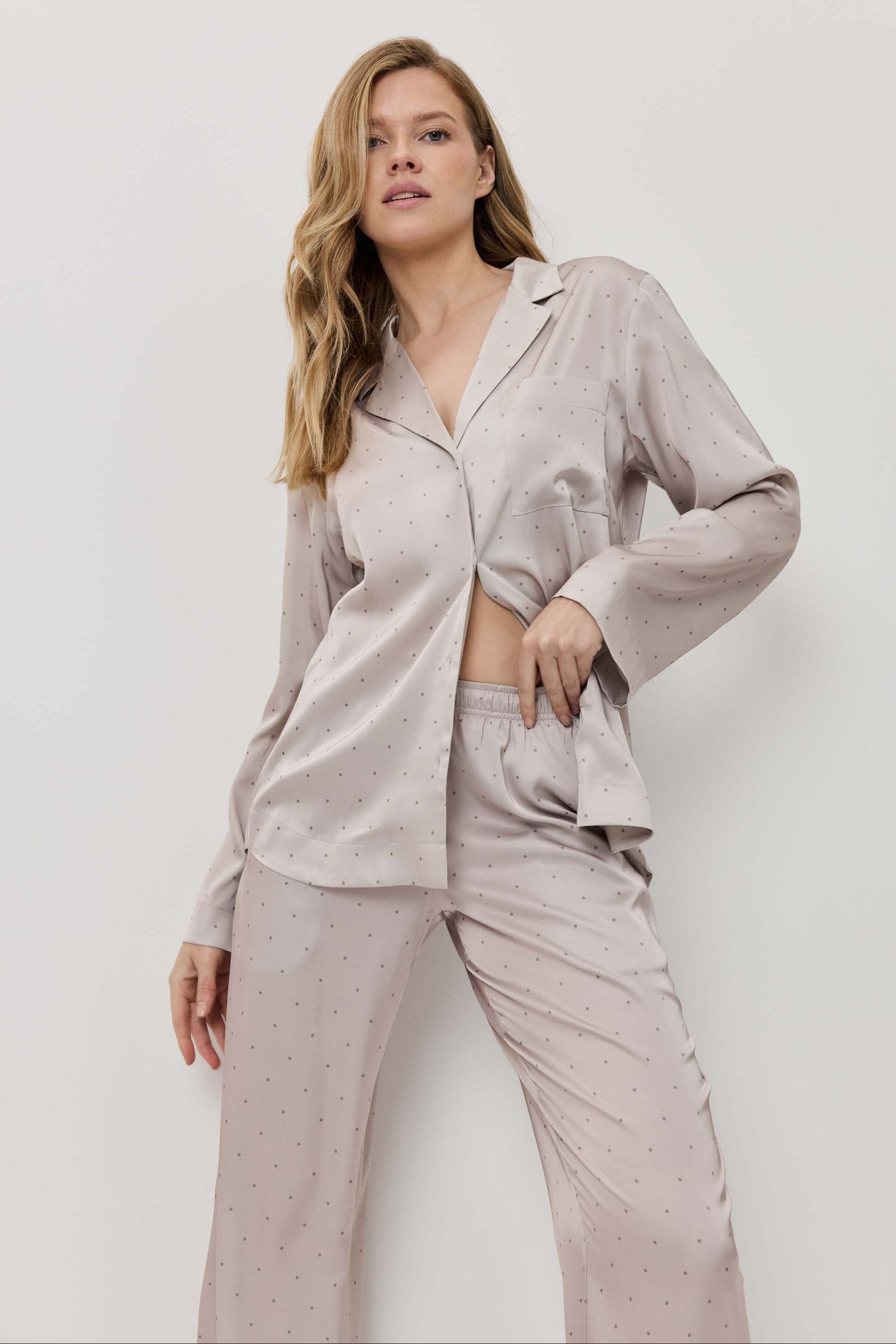 Woman wearing a light gray pajama set against a white background