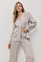 Woman wearing a light gray pajama set against a white background