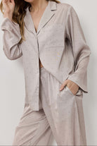 Woman wearing a light gray pajama set with small patterns on a white background