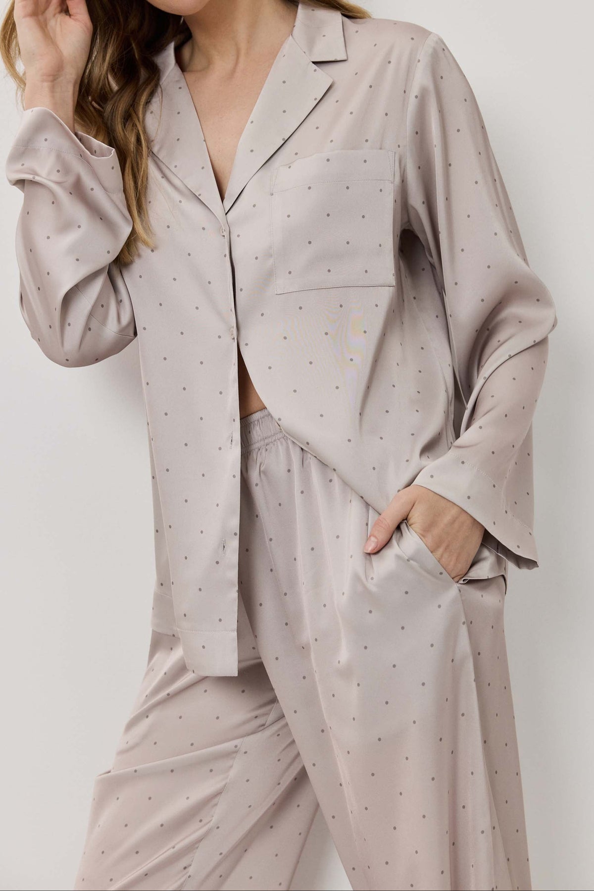 Woman wearing a light gray pajama set with small patterns on a white background
