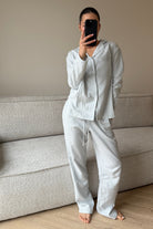 Person wearing a light-colored pajama set standing in a room with a sofa.